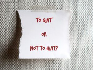 a piece of paper that says "to quit or not to quit?" taped to a wall