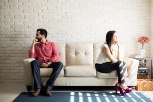man and woman sitting on opposite sides of a couch and looking away from each other